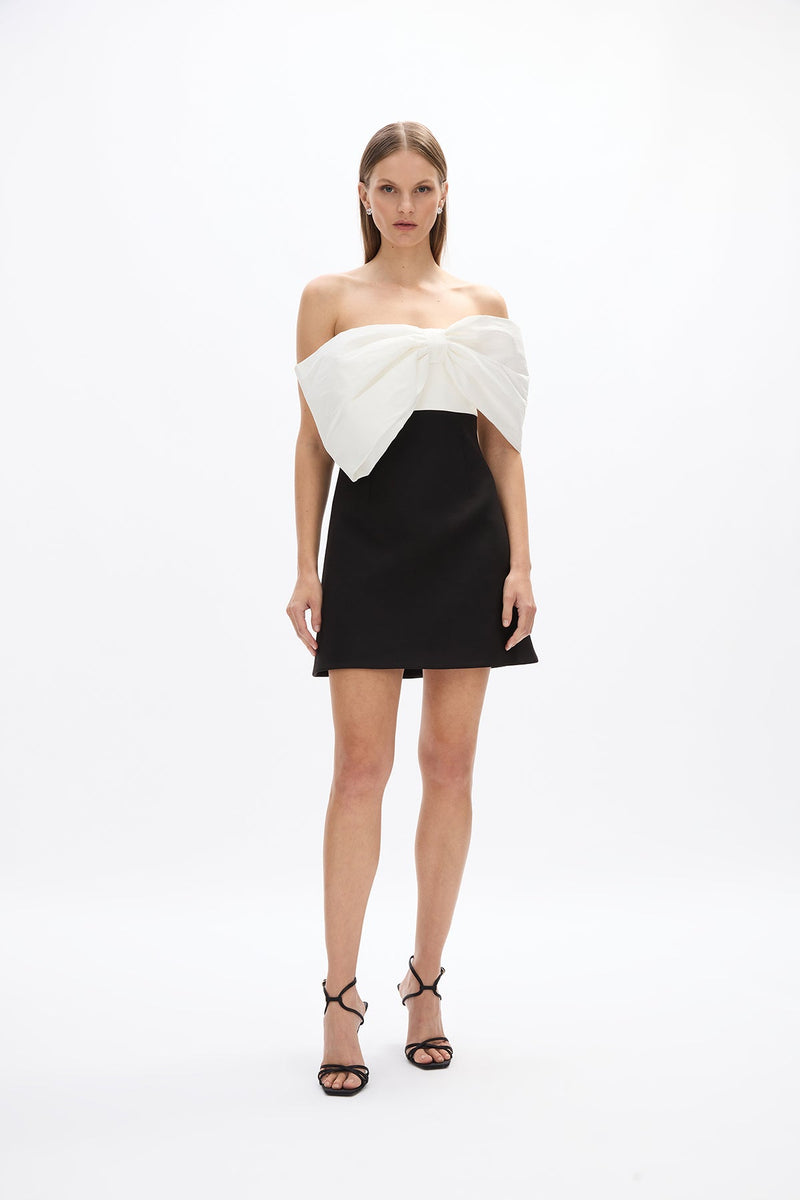 Kace Mini: chic black and white mini dress with voluminous off-the-shoulder bow detail and internal boning, perfect for special events.